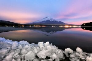 Captivating sunset over Mount Fuji reflected in a serene lake with icy foreground.